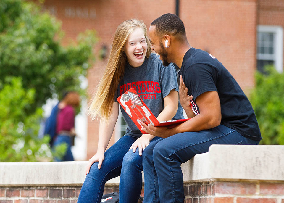 students resting on wall in lower quad