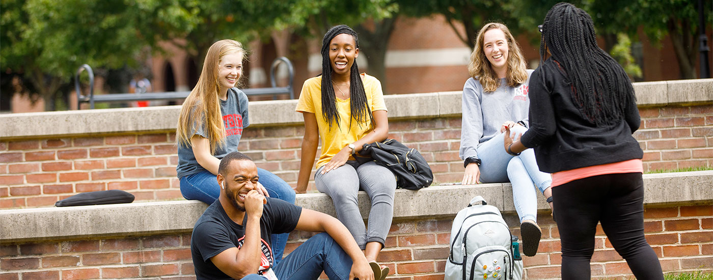A group of Frostburg State students laugh while sitting outside
