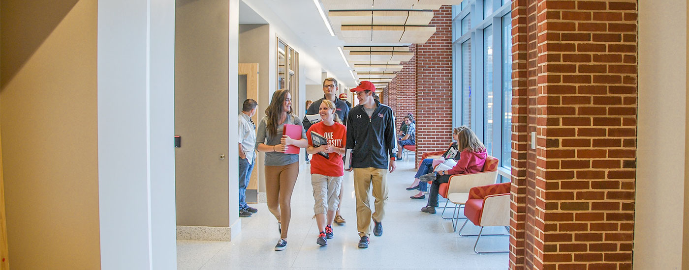 Students walk down a hallway and laugh in between classes