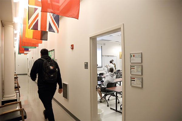A student walks underneath a group of international flags when exiting a classroom