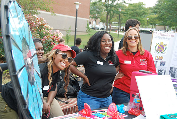 Girls smile at visitors to their booth during a student organization event