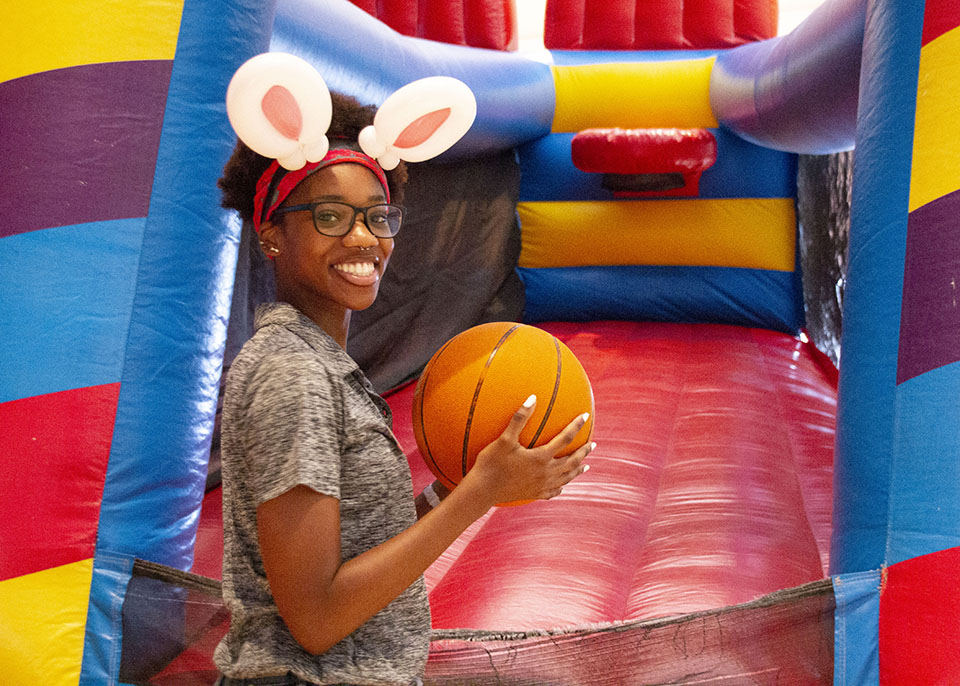 female student wearing bunny ears headband and holding a basketball